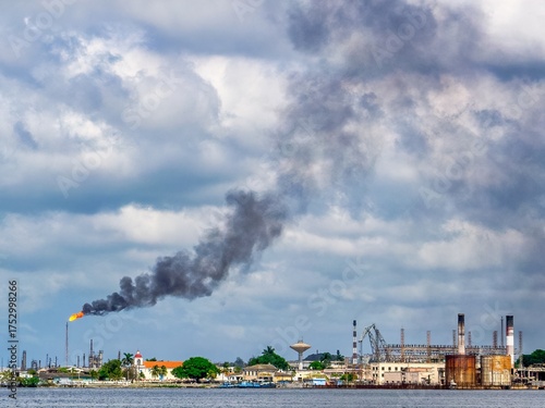 Industrial skyline in Havana with smoke rising under dramatic clouds. Industrial skyline in Havana with flare smoke and dramatic clouds, reflecting tension between nature and progress.