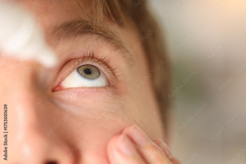 Naklejka premium Man applying eye drops on light background, closeup. Space for text