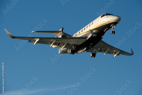 A private jet approaches the airfield against a backdrop of a partly cloudy sky. Airplane in the blue sky with white clouds.