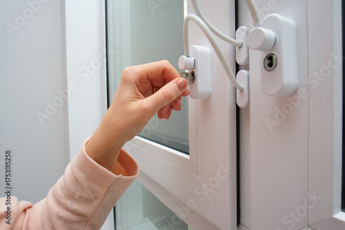 Foto Woman's hand turning white window lock with safety cable