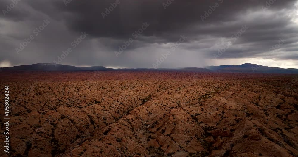 Storm clouds brewing over dramatic desert terrain with lightning strike, aerial