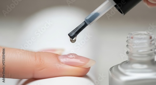 Clear top coat nail polish drop on woman finger during manicure procedure. Professional beauty treatment at nail salon concept.