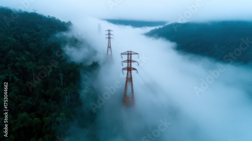 A captivating aerial view of towering power lines extending through a misty forest, evoking a sense of mystery and tranquility in the great outdoors.