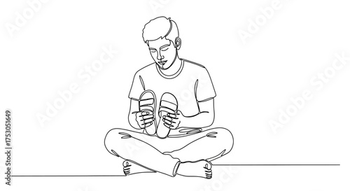 Young man sitting cross-legged holding flip-flops, deep in thought