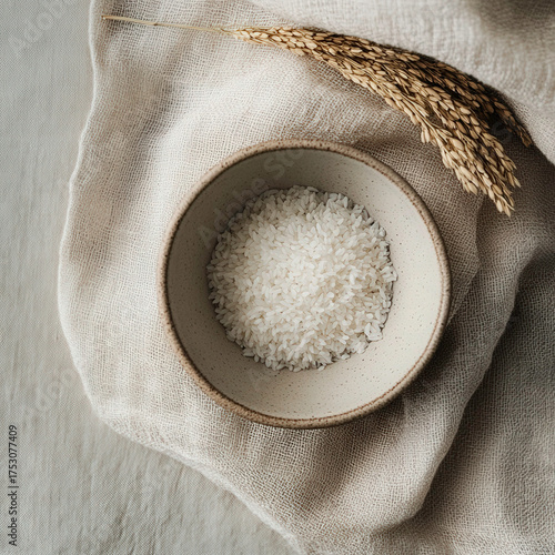 A white bowl filled with white rice is placed on a white cloth