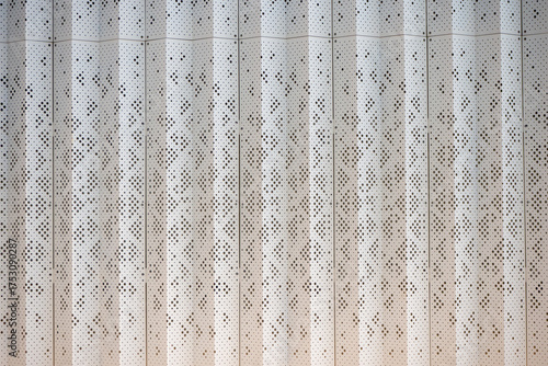 Perforated metal facade with vertical striped pattern. Architectural texture for industrial, modern or commercial building design. Close-up. Real photo