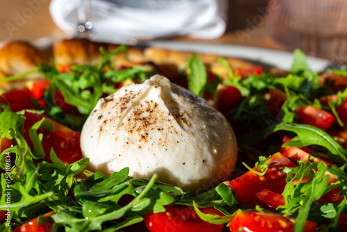 Freshly made pizza served on table with burrata, cherry tomatoes and rocket