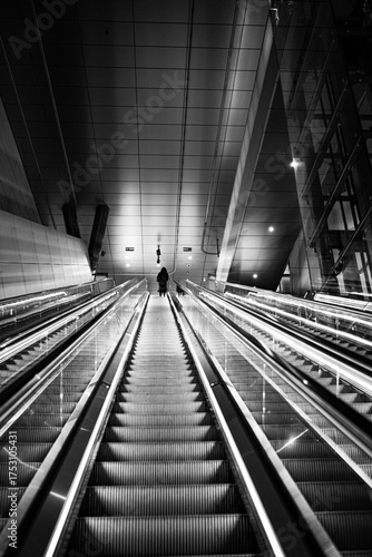 Low angle view of person standing on an escalator black and white