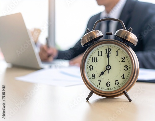 Vintage alarm clock on an office desk with a businessman working in the background, symbolizing a deadline. Generated image