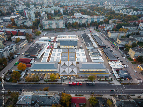 Aerial drone shot of Kalvarijų Market in Vilnius, Lithuania at early autumn morning, warm light over colorful stalls and roofs.