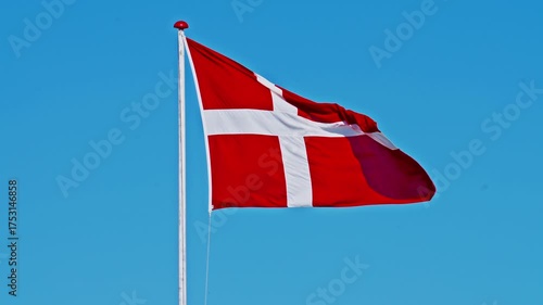 Danish flag flutters in the wind against the background of the blue sky in the wind 