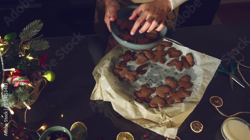 Arranging Freshly Baked Gingerbread Cookies on a Cozy Christmas Table