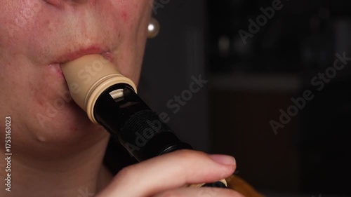 Recorder flute played near mouth with focused expression