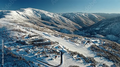 Breathtaking aerial view of a ski resort nestled in snow-covered mountains under a clear blue sky