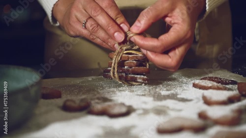 Hands Tying Twine Around Heart-Shaped Gingerbread Cookies for Holiday Gift