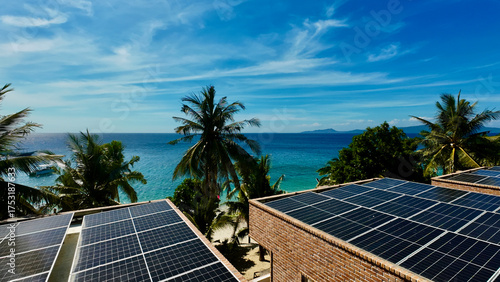 Solar panels on tropical resort rooftops overlook turquoise sea and palm trees. The image captures sustainable energy blending with paradise island scenery on a sunny day.