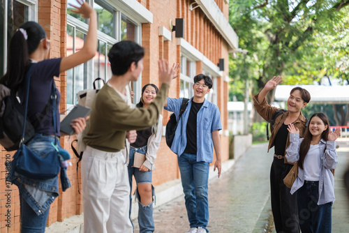 Group of university students happily greeting each other outside a campus building.