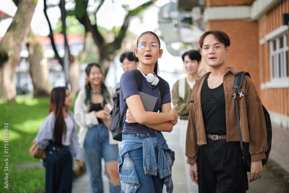 Obraz premium Group of diverse students laughing and socializing in front of a school building.