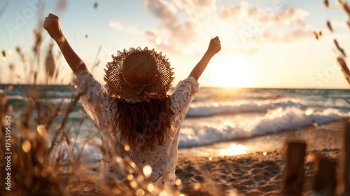 A joyful woman stands with her arms raised towards a stunning sunset on the beach, capturing a moment of pure happiness and connection with nature's beauty.
