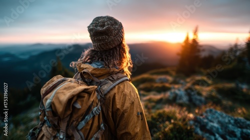 A lone adventurer stands atop a mountain peak, gazing at the magnificent sunset, evoking feelings of awe and reflection amidst the beauty of nature and exploration.