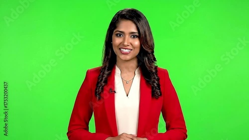 Female anchor smiling while delivering headlines, isolated on a green screen background.