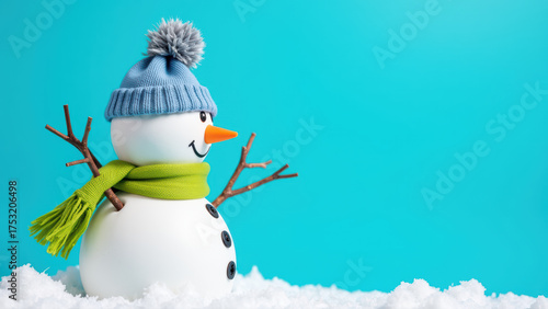 Cheerful snowman wearing blue hat and green scarf stands in fresh snow against bright turquoise background, evoking playful winter scene