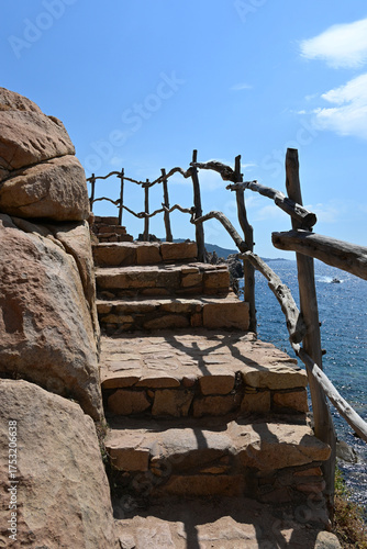 Scenic view of Costa Paradiso, Sardinia, Italy with red cliffs and a coastal path leading to Li Cossi Beach, a hidden gem surrounded by turquoise waters and dramatic rock formations