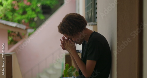 Papier peint Young boy in emotional distress, sitting against wall, hands covering face, Afri