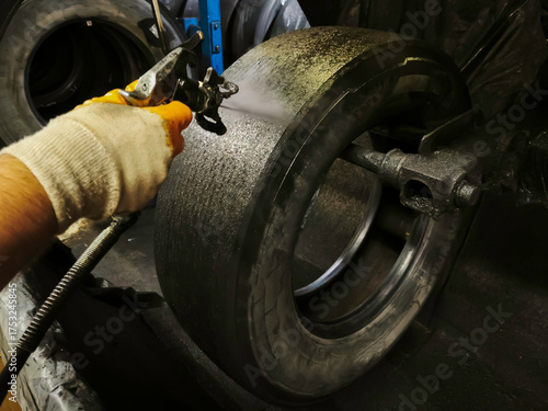 In the tire retreading workshop, cement solution is applied to the buffed surface before the tire retreading process.