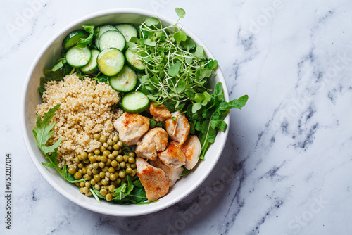 Balanced quinoa, arugula, chicken, cucumber and pea lunch bowl.
