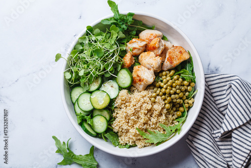 Balanced quinoa, arugula, chicken, cucumber and pea lunch bowl.