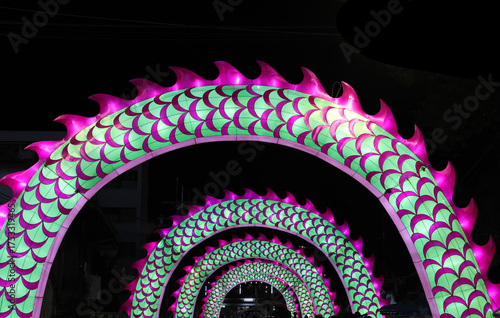 Curved walkway design with dragon symbols decorated with pink and green lighting during Chinese New Year festival