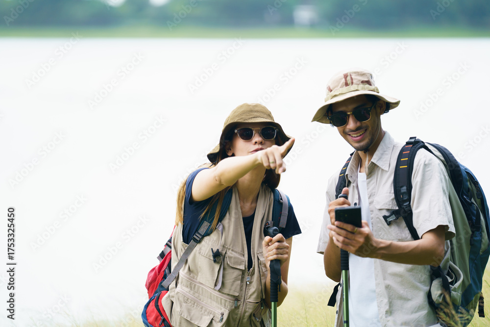 Fototapeta premium Asian hikers checking map on smartphone during outdoor adventure.