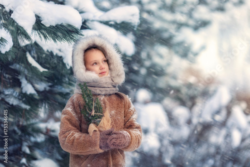 Girl in the snow forest with a small Christmas tree in her hands