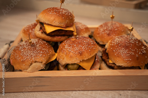 Homemade cheeseburgers on a wooden tray. A custom homemade dish. Large meat patties with buns sprinkled with sesame seeds. Slightly greedy.