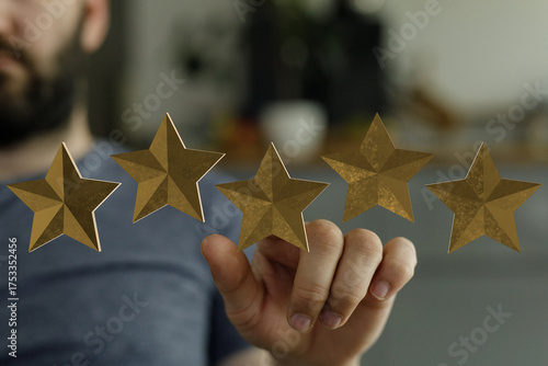Photos A close-up of a hand touching five golden stars, implying a rating or feedback system