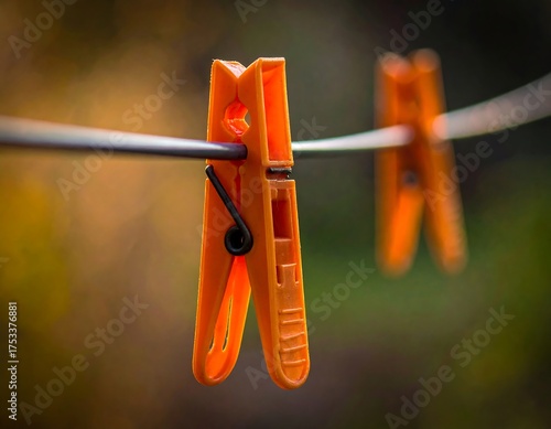 Close-up of orange clothespins clamped onto a wire outdoors, blurred background