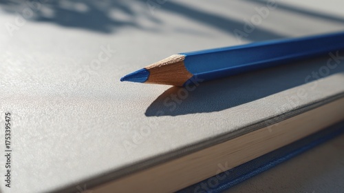 Close-up of a vibrant blue colored pencil resting on a light gray notebook