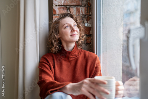Fotografía Serene woman relaxing takes coffee break looking to window with positive thoughts