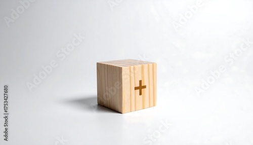 A single wooden cube with a plus sign etched on one side is isolated against a seamless white backdrop, casting a soft shadow
