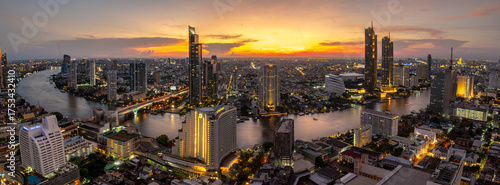 Beautiful panoramic view of Bangkok, Thailand at sunset. The iconic Chao Phraya River gracefully winds through the city, reflecting the vibrant twilight sky. This stunning cityscape captures the seren