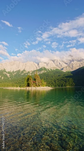Eibsee Lake, Mountain Slopes with Forest, Island and Zugspitze Massif at Sunset. Ripple on Water. Bavaria, Germany. Vertical Video