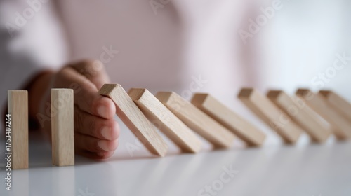 Businesswoman stopping a chain reaction of wooden dominoes, representing crisis management and business decision-making