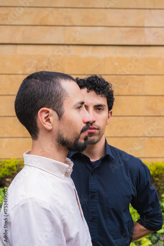 Two young adult twin brothers posing against a wall outdoors, expressing family connection
