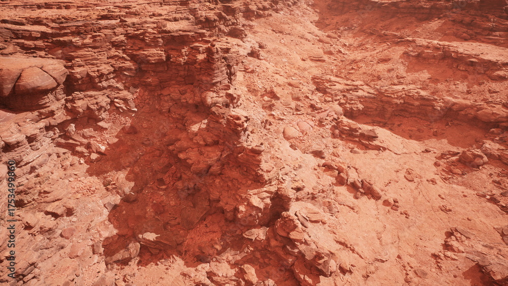 Fototapeta premium Warm sunlight casts deep shadows across the rugged red rocks of the canyon. The intricate patterns and layers create a mesmerizing view that invites curiosity and exploration during golden hour.