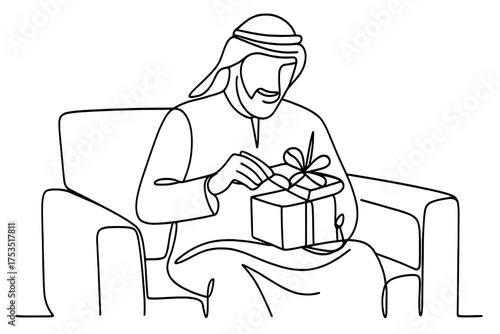 Man opens a beautifully wrapped gift while sitting comfortably on a couch at home during a special occasion