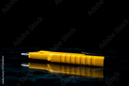 Hobby knife bright yellow on dark marble surface and Black background in studio shot. Horizontal format.