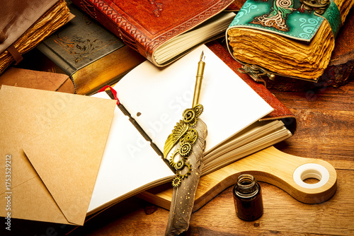 A creative still life arrangement featuring vintage leather journals, an open blank notebook, a steampunk feather pen, a kraft paper envelope and an ink bottle placed on a rustic wooden desk.