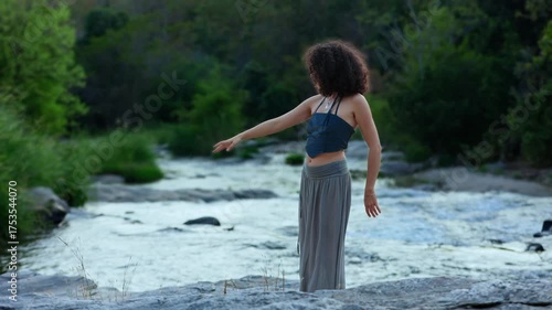 A graceful dancer poses by a serene river, capturing the essence of nature and movement, embodying freedom and connection with the natural world.
