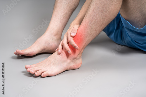 Joint inflammation, foot pain, man suffering from feet ache on gray background, podiatry concept